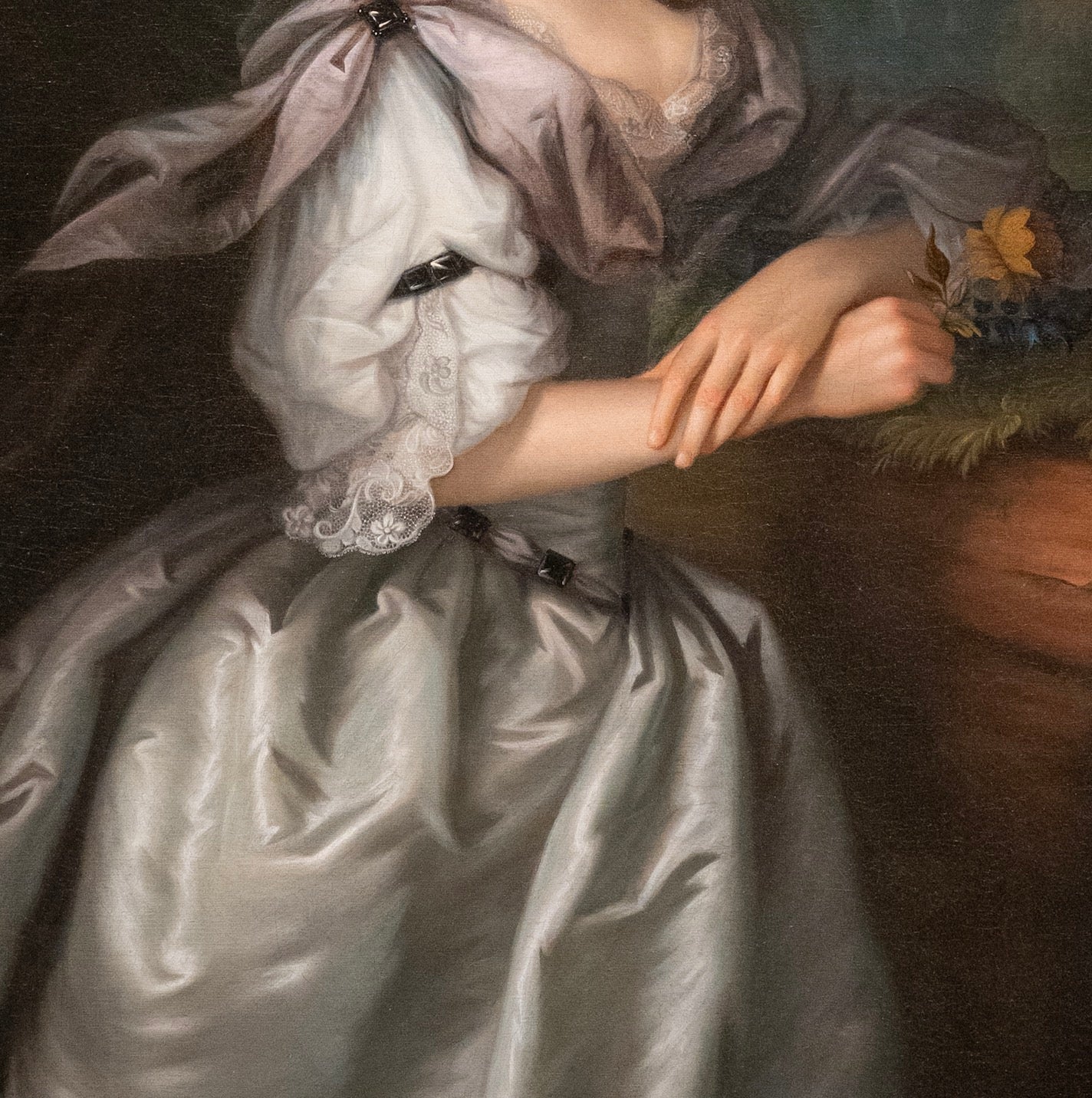 Portrait of a person in a white dress with lace details, wearing a pink headscarf.
